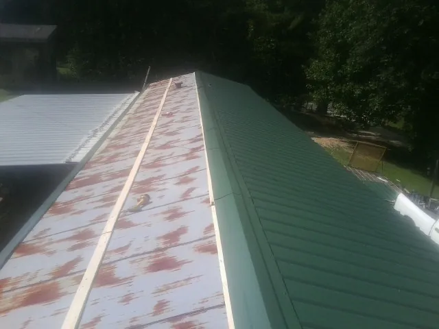 Old rusted panels beside newly installed green metal roofing — Wind Damage Roof Repair by Roofing Brothers in Sheldon