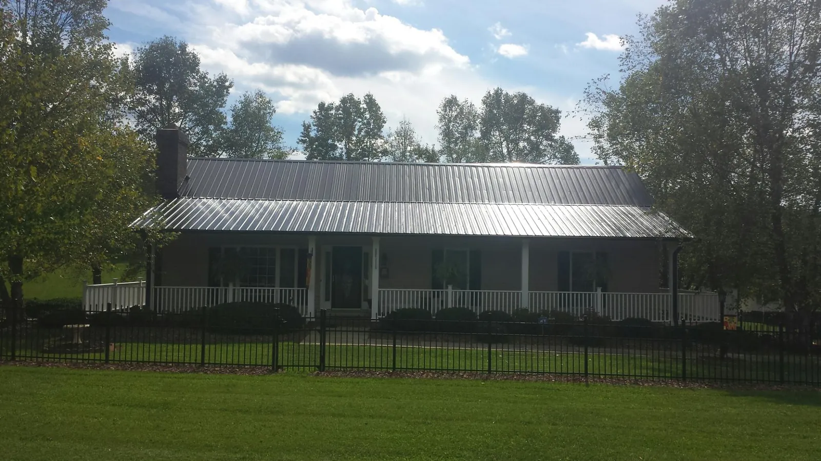 Gray metal roof on a brick ranch with a full width front porch — Gutter Guard Installation work by our crew in Sheldon